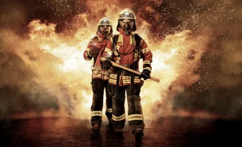 Symbolbild für Krise: Feuerwehrmänner in Montur vor einer Explosion.