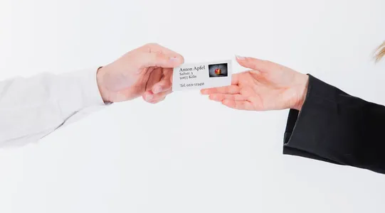 Eine Hand im weißen Ärmel übergibt einer Hand im schwarzen Ärmel eine Visitenkarte. Mit Visitenkartenscanner würde das anders aussehen.