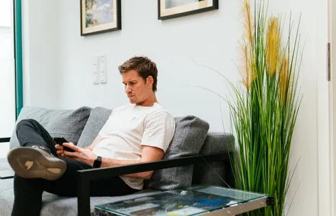 42he-Gründer Axel von Leitner sitzt im Büro auf der Couch und schaut auf sein Handy.