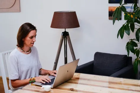 Anja arbeitet am Laptop, im Hintergrund ein Büro.