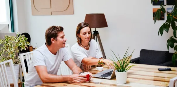 Anja und Axel im Gespräch am Laptop am Schreibtisch im Büro.