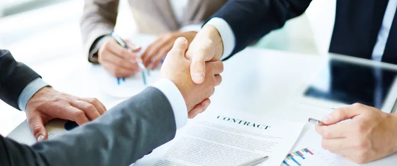 Ein Handschlag zwischen Geschäftsmännern. Man sieht nur Arme und Hände.