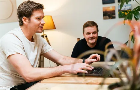 Axel und Christian überlegen sich Kundenbindungsmaßnahmen am Laptop.