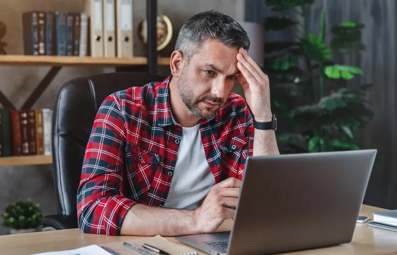 Agenturinhaber betrachtet stirnrunzelnd seinen Laptop.
