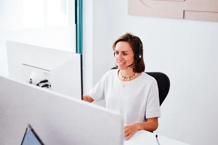 Anja sitzt am Rechner und telefoniert mit einem Kunden.