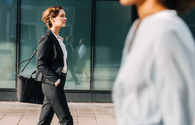 Formell gekleidete Mitarbeiterin einer Agentur läuft durch die Straßen.