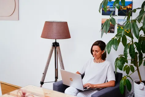 Anja sitzt mit Laptop im Sessel und verwaltet Adressen mit CentralStationCRM.