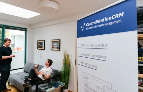 Axel und Christian reden über Anwendungsbeispiele von CRM Software. Im Vordergrund: Ein Banner von CentralStationCRM.