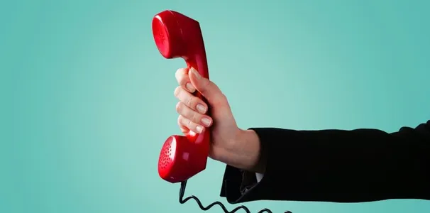 Eine Hand, die einen Telefonhörer hält.